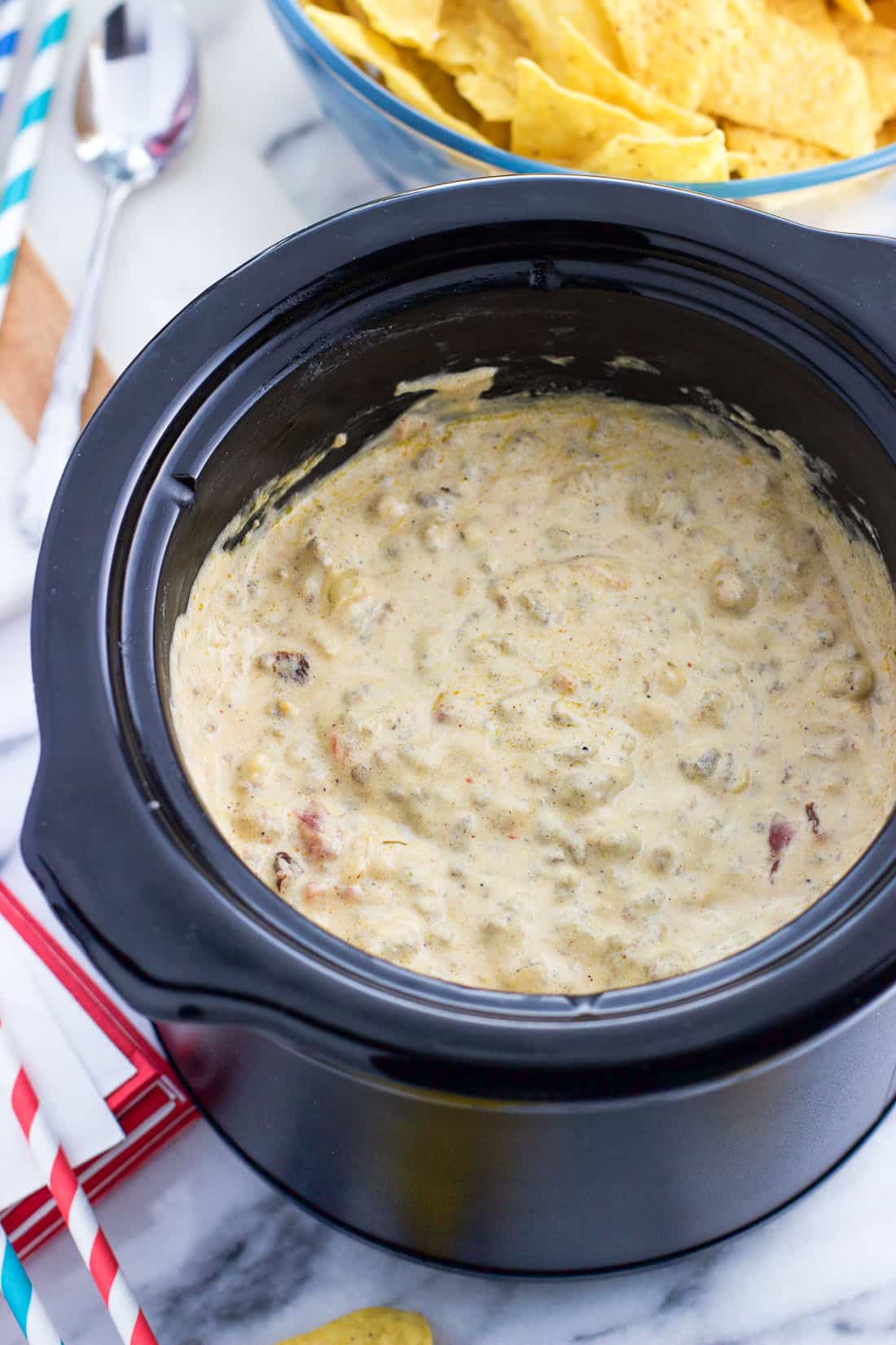 A small slow cooker filled with hot queso dip.