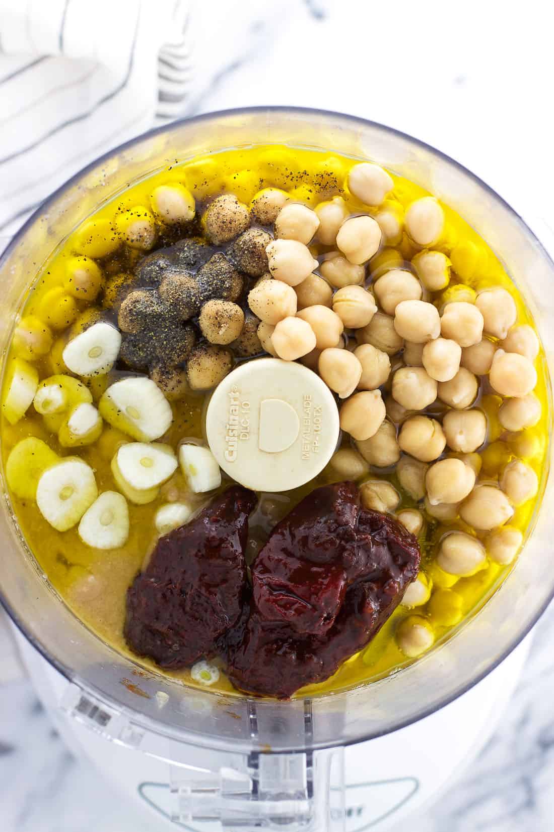 All of the ingredients in the bowl of a 7-cup food processor before blending