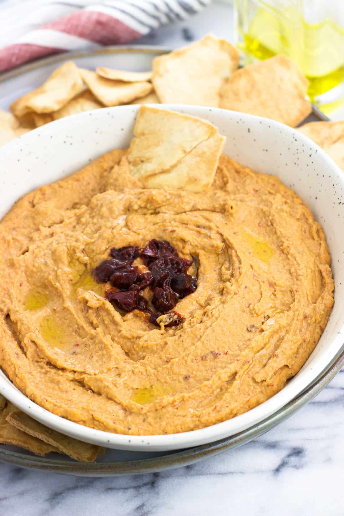 A pita chip scooped into the bowl of hummus