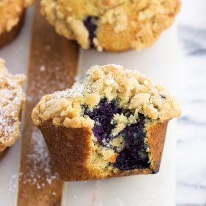 A side view of a big bite taken out of a muffin on a serving board