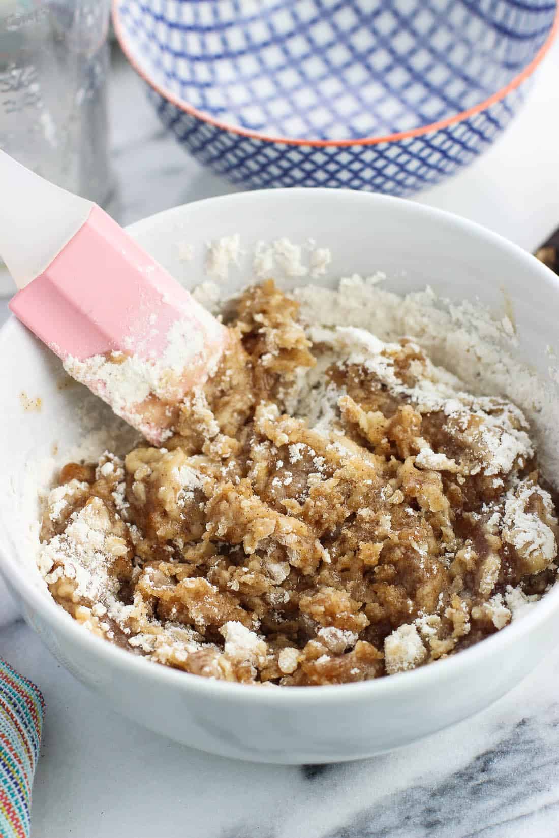 Flour being stirred into the crumb topping mixture in a bowl.