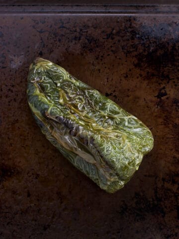 A roasted poblano pepper on a baking sheet.