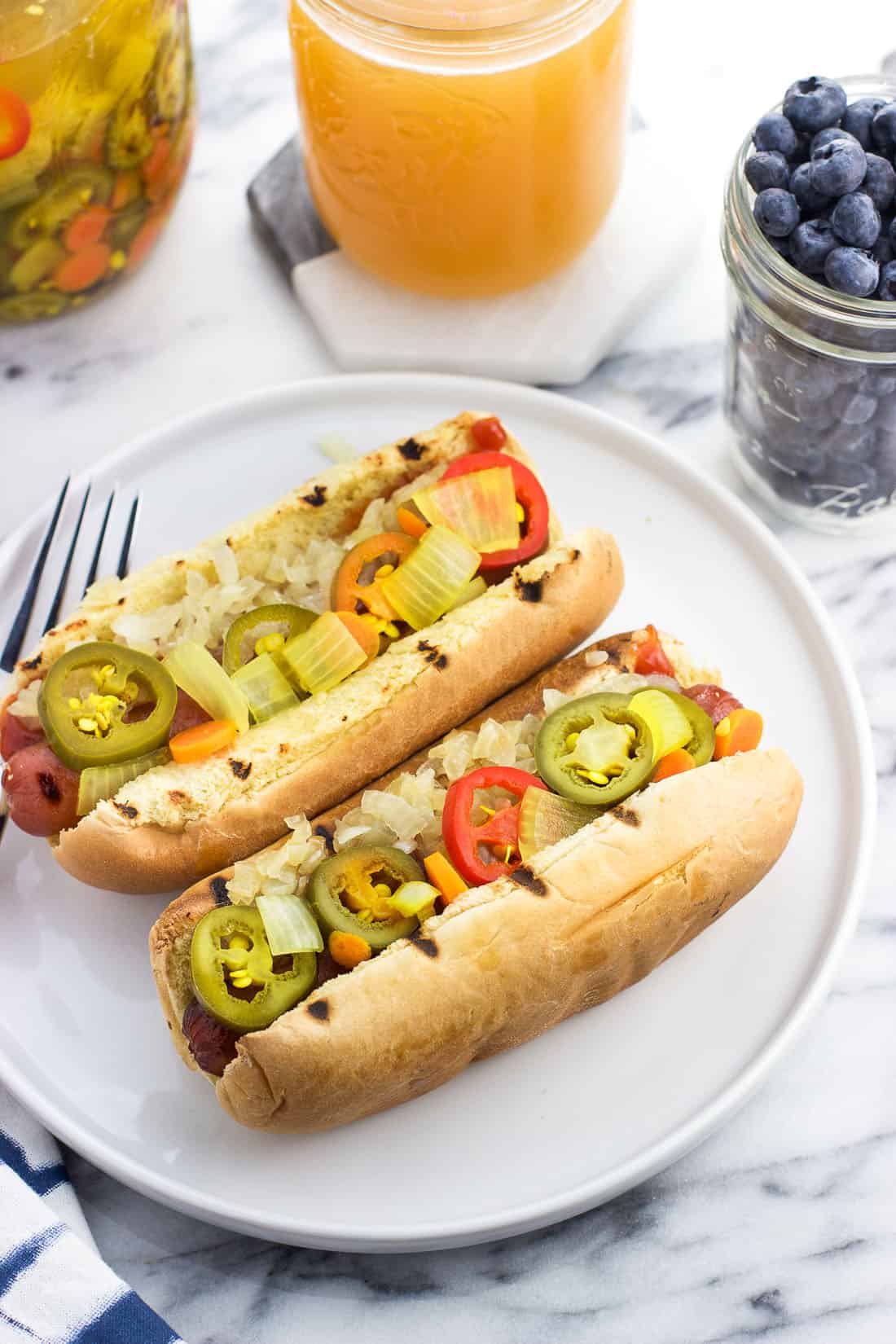 Two dressed hot dogs on a plate.
