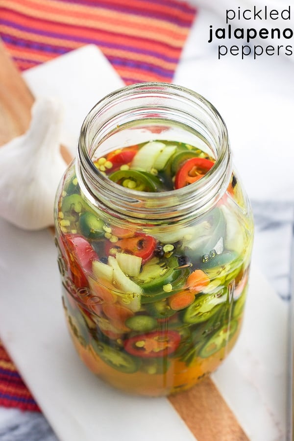 A jar of pickled peppers in liquid with the text name of the recipe in the upper right corner of the image