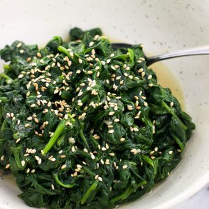 A serving dish of sauteed spinach with a spoon