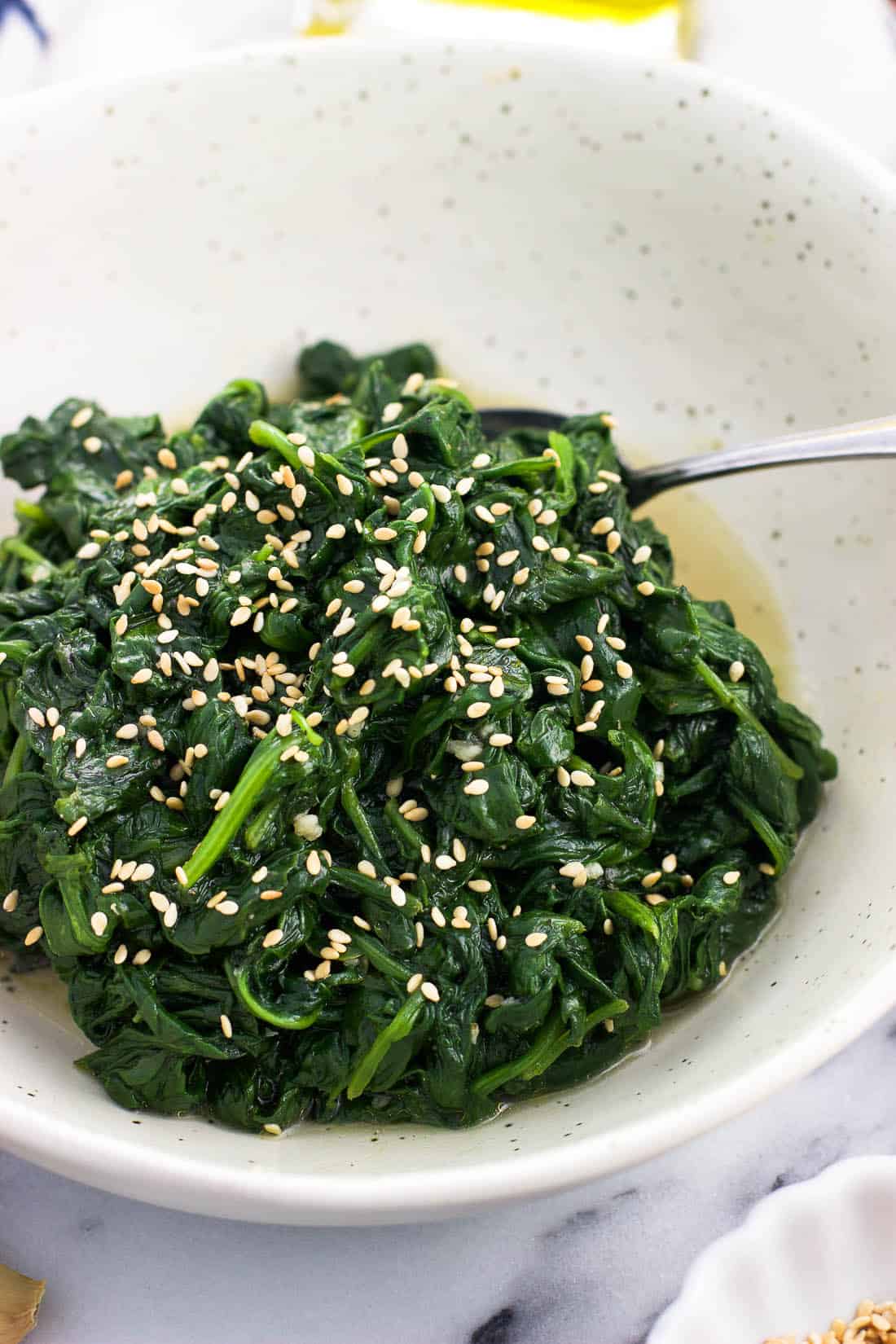 Sauteed spinach in a ceramic serving bowl with a spoon