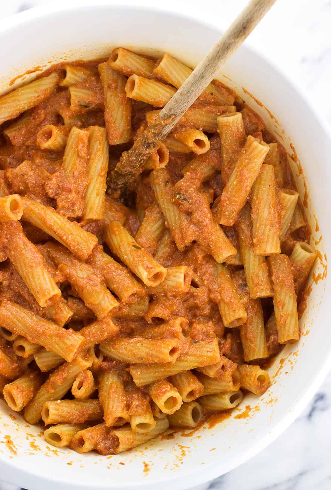 Cooked ziti stirred into the bowl with the sauce and ricotta cheese.