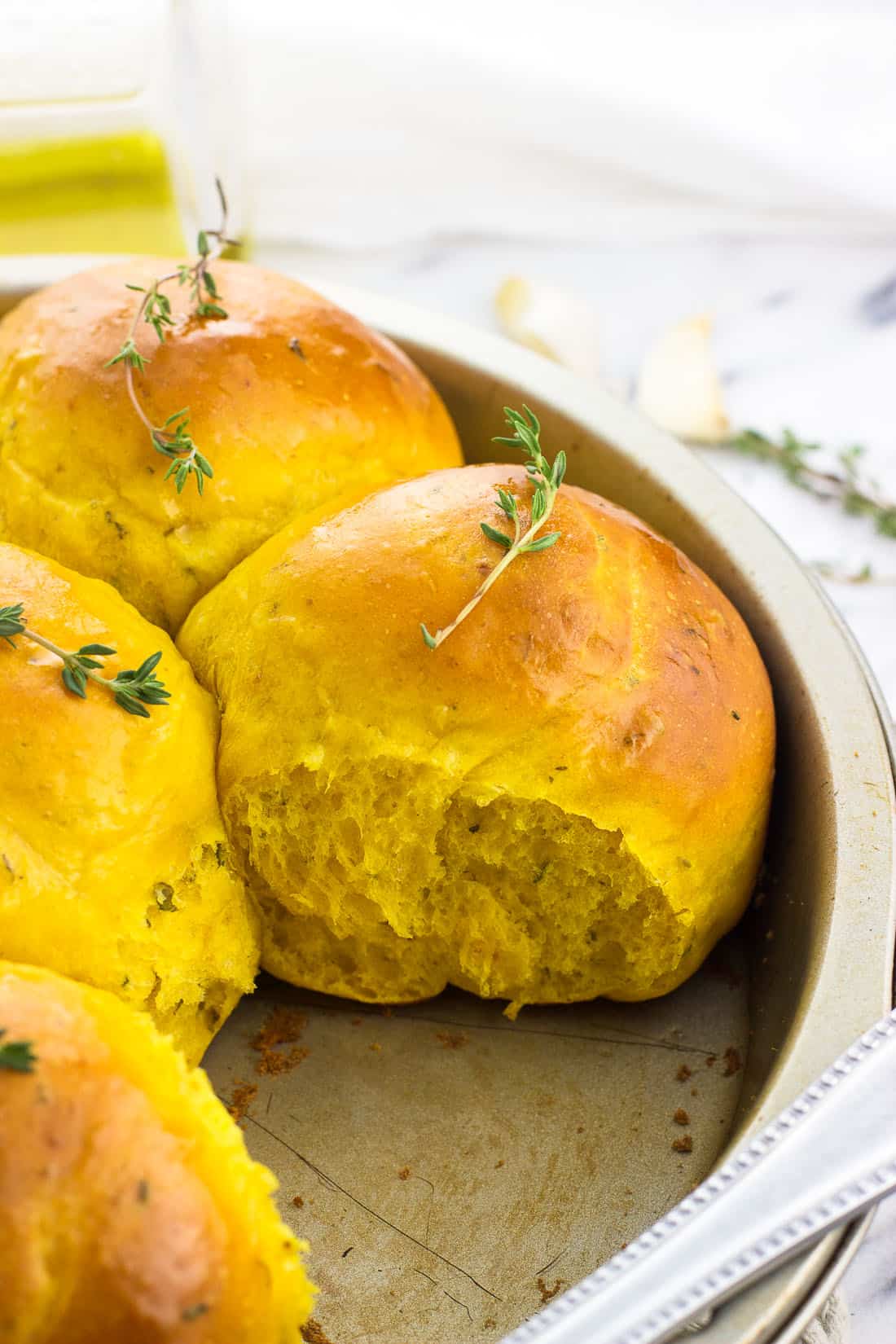 Pull-apart pumpkin rolls in a round cake pan topped with fresh thyme sprigs