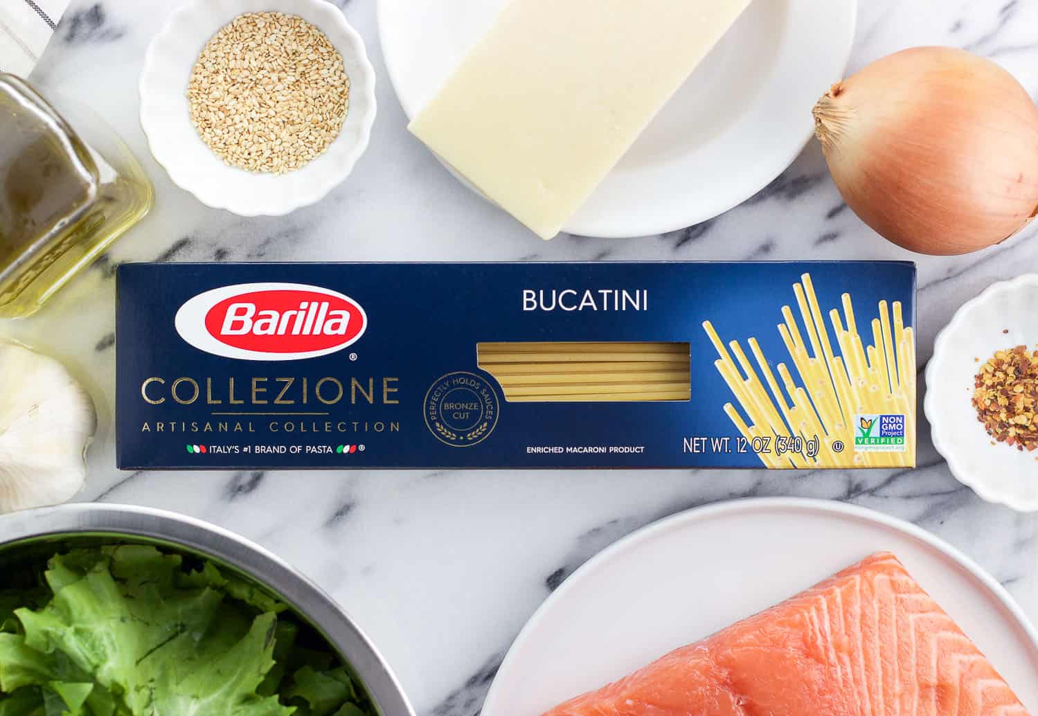 A box of Barilla Bucatini on a marble board surrounded by the rest of the recipe ingredients