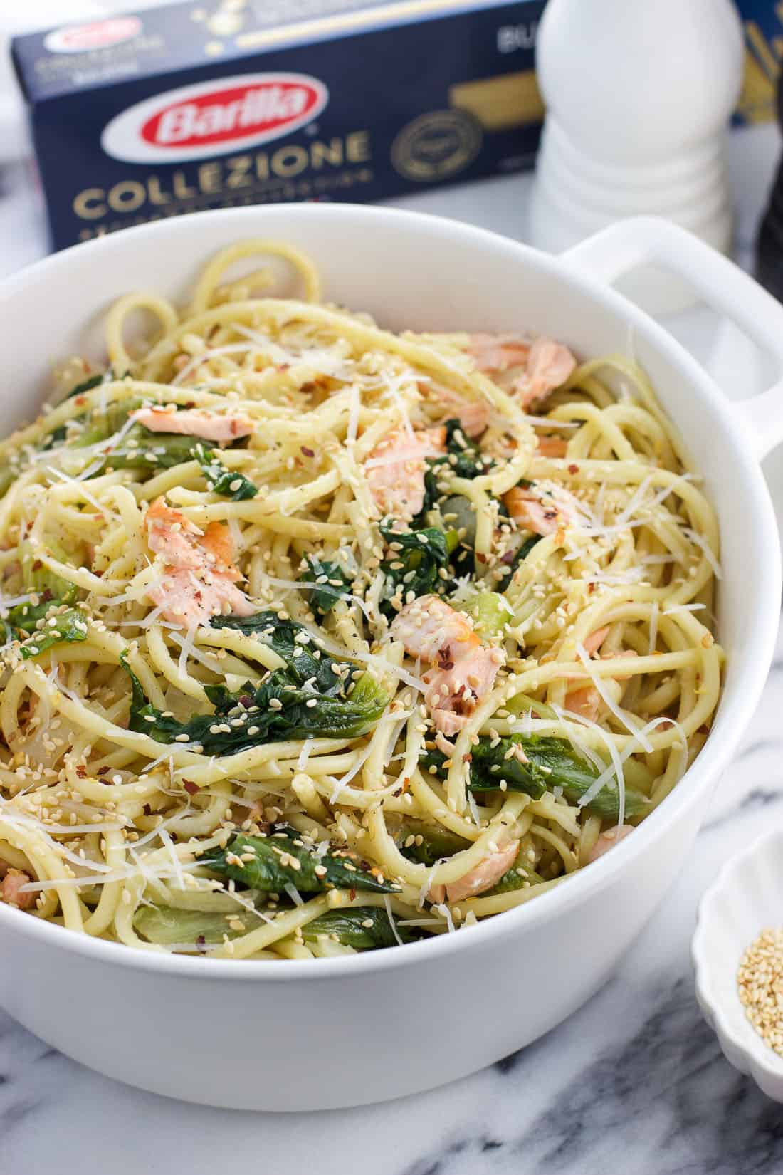 A large ceramic pot filled with pasta and topped with sesame seeds.