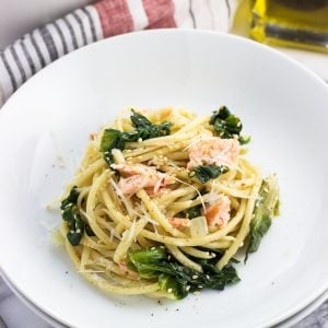 A serving of pasta, salmon, and escarole in a shallow dish