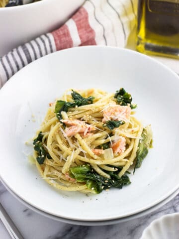 A serving of pasta, salmon, and escarole in a shallow dish