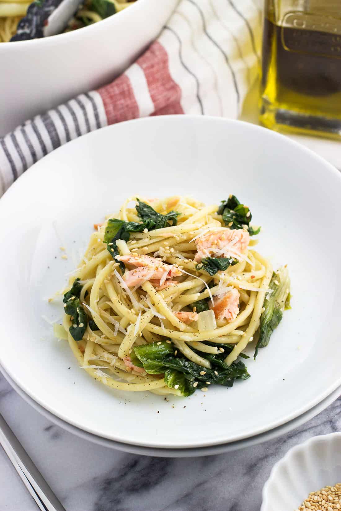 A serving of pasta, salmon, and escarole in a shallow dish.