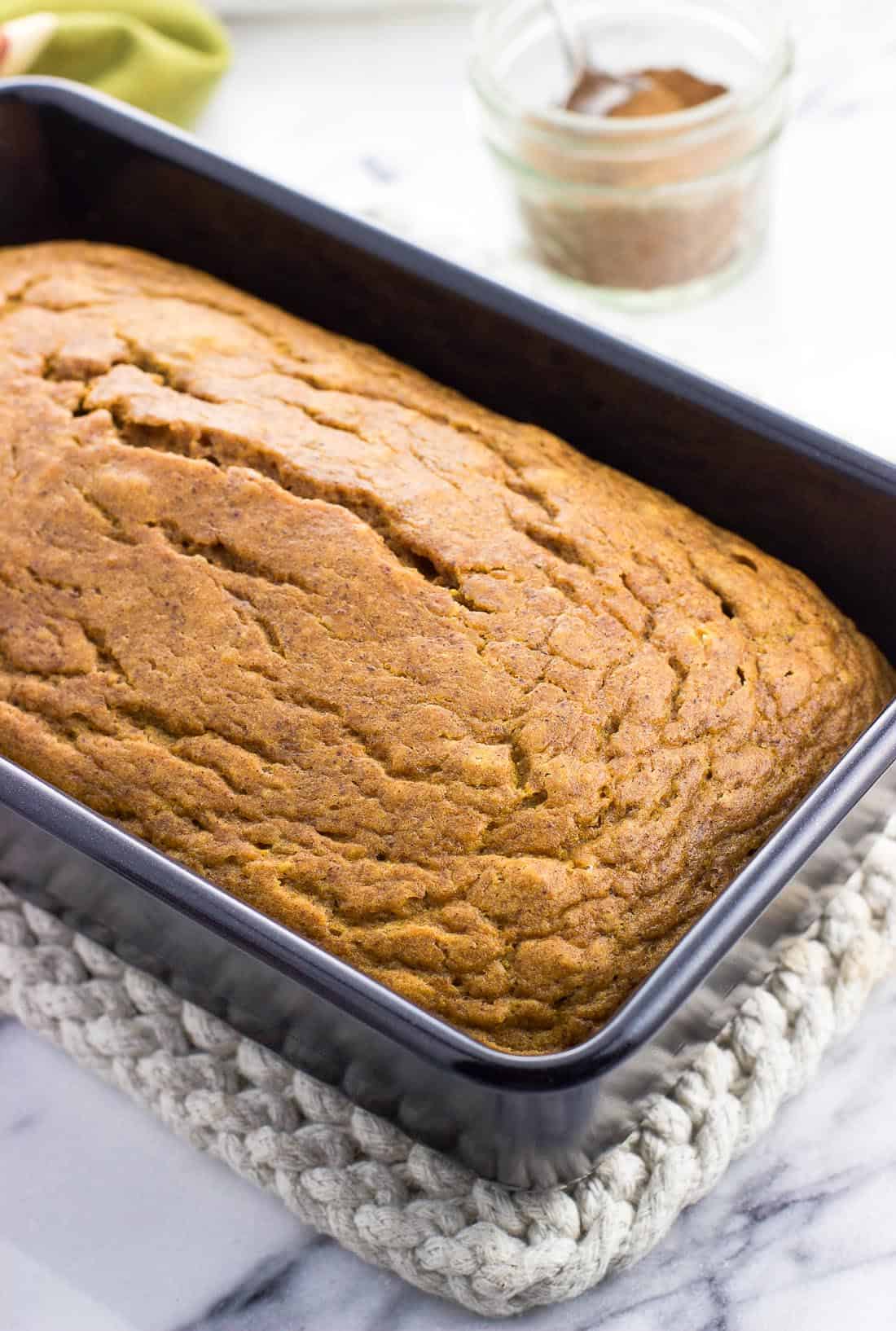 A loaf of pumpkin bread cooling in a loaf pan