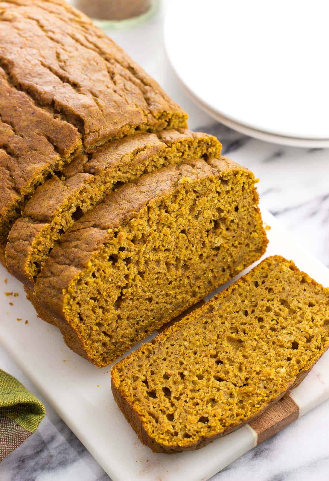 A loaf of half-sliced pumpkin bread on a serving tray.