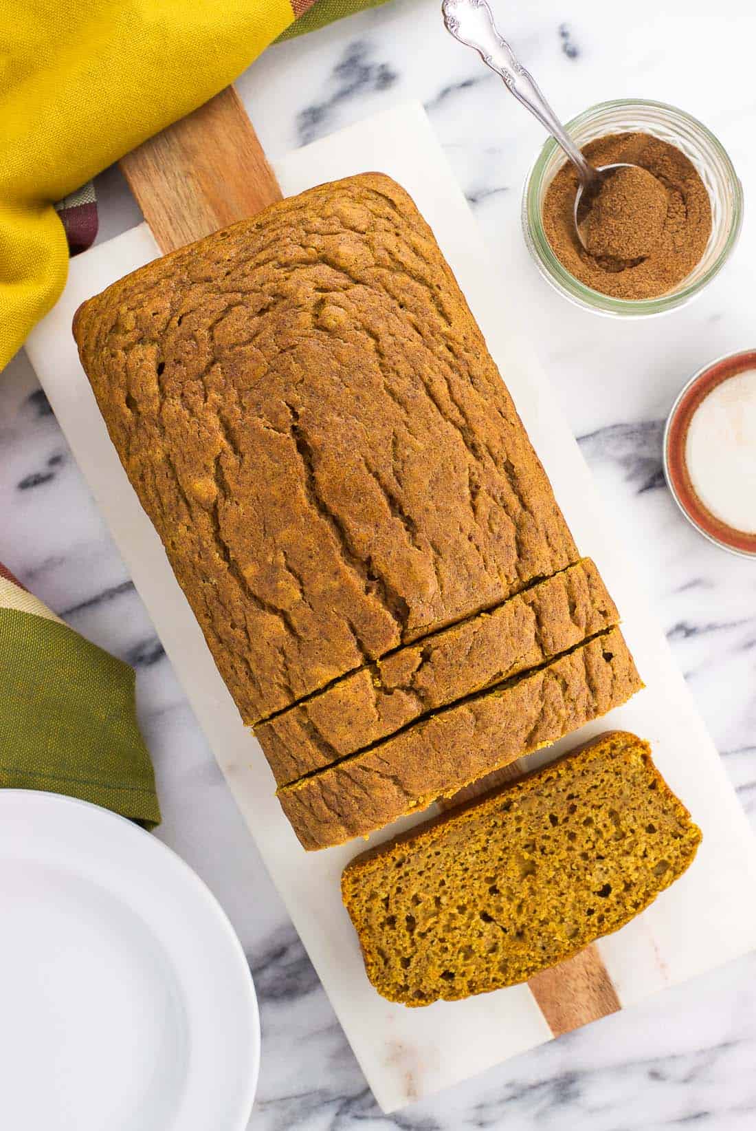 An overhead shot of a loaf of pumpkin bread beginning to be sliced