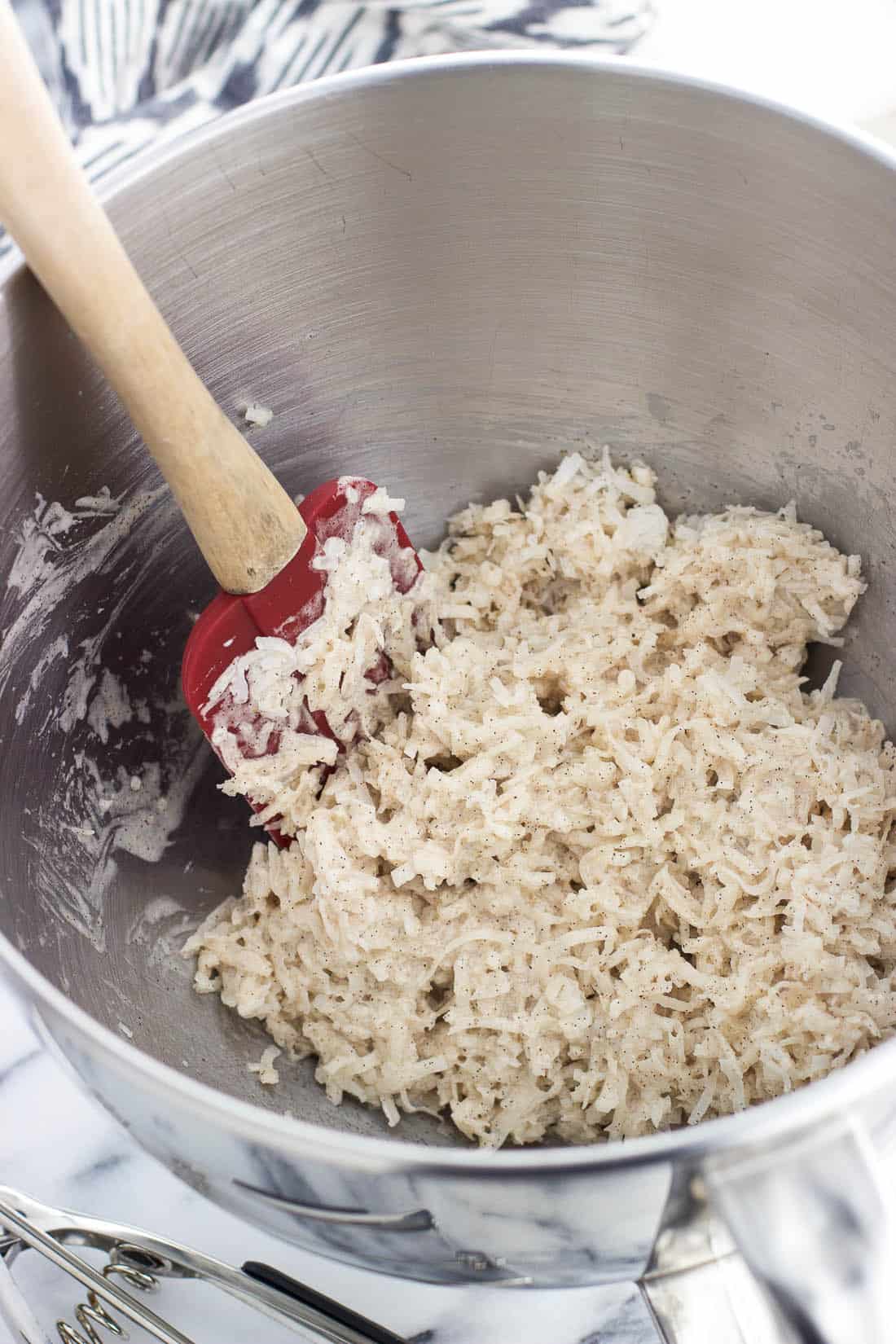 Macaroon cookie dough in a metal mixing bowl with a spatula.