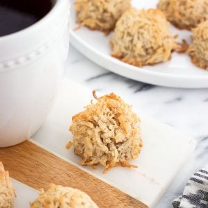 Macaroons on a marble board surrounded by more macaroons on a plate and a mug of chai tea