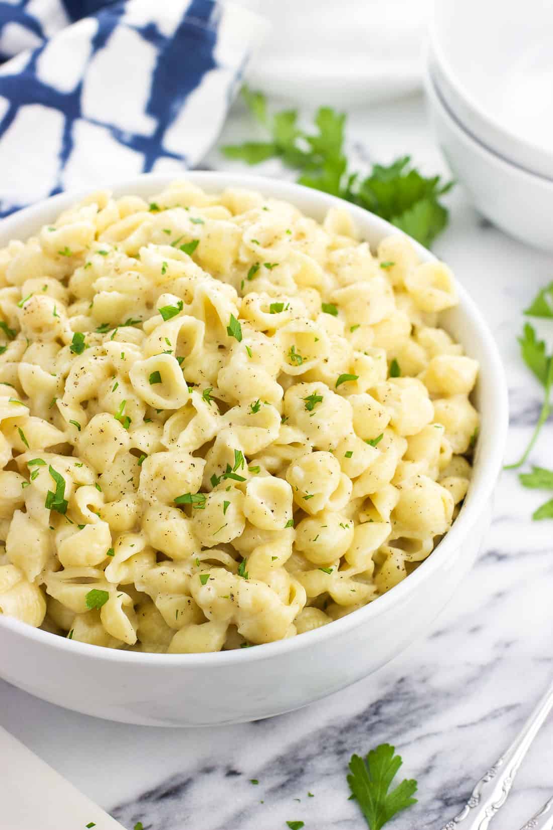 A bowl of mac and cheese garnished with bits of parsley