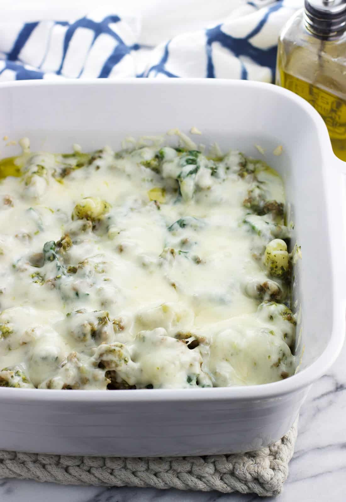 Cheese melted on top of the gnocchi and sausage mixture in a baking dish