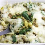A serving spoon lifting a big scoop of the gnocchi bake out of the baking dish