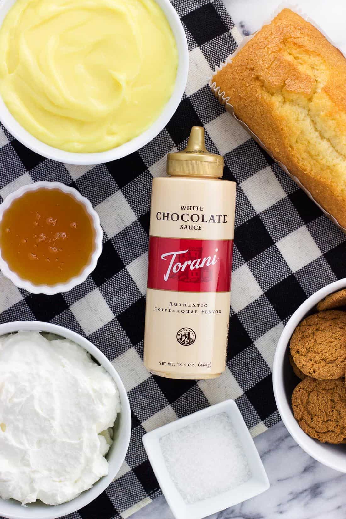 An overhead shot of the recipe ingredients in separate bowls surrounding a bottle of Torani white chocolate sauce