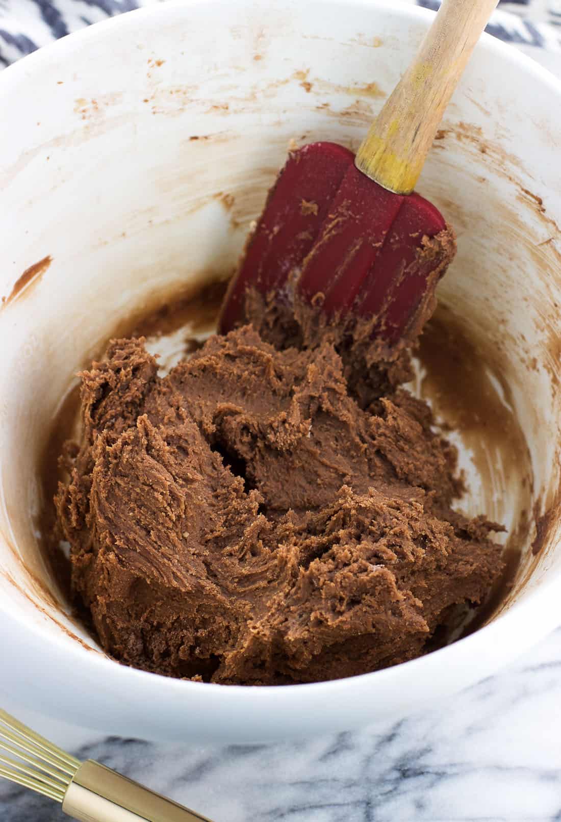 Chocolate cookie dough in a mixing bowl with a spatula.