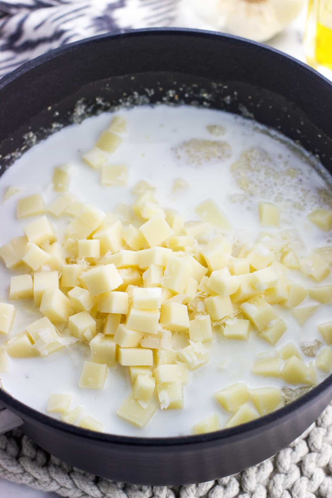 Cheese and milk poured into a saucepan full of cooked grits