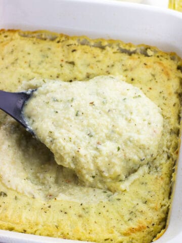 A big spoonful of grits being lifted out of the pan