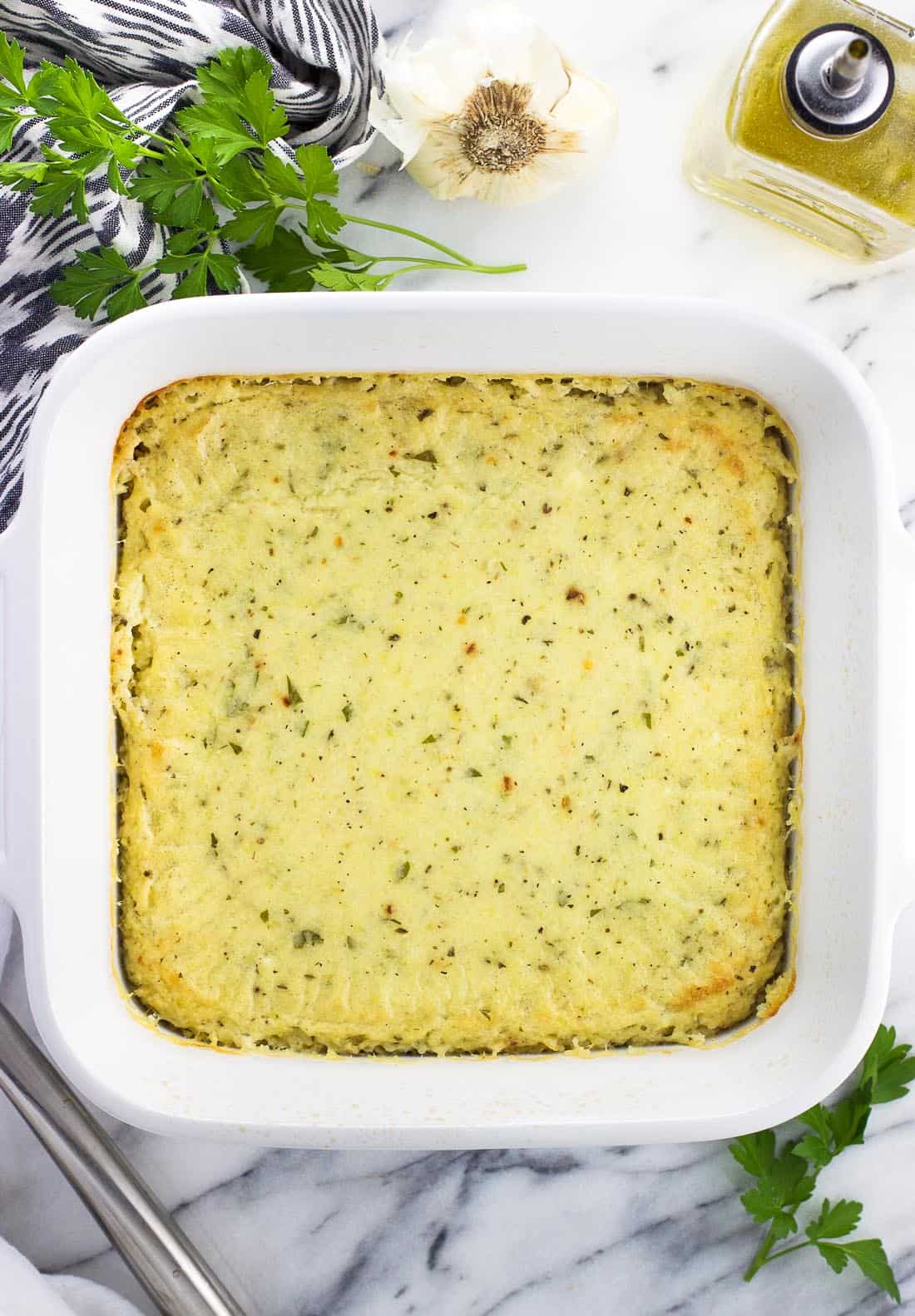 An overhead shot of the baked Italian grits in a deep, square ceramic baking dish