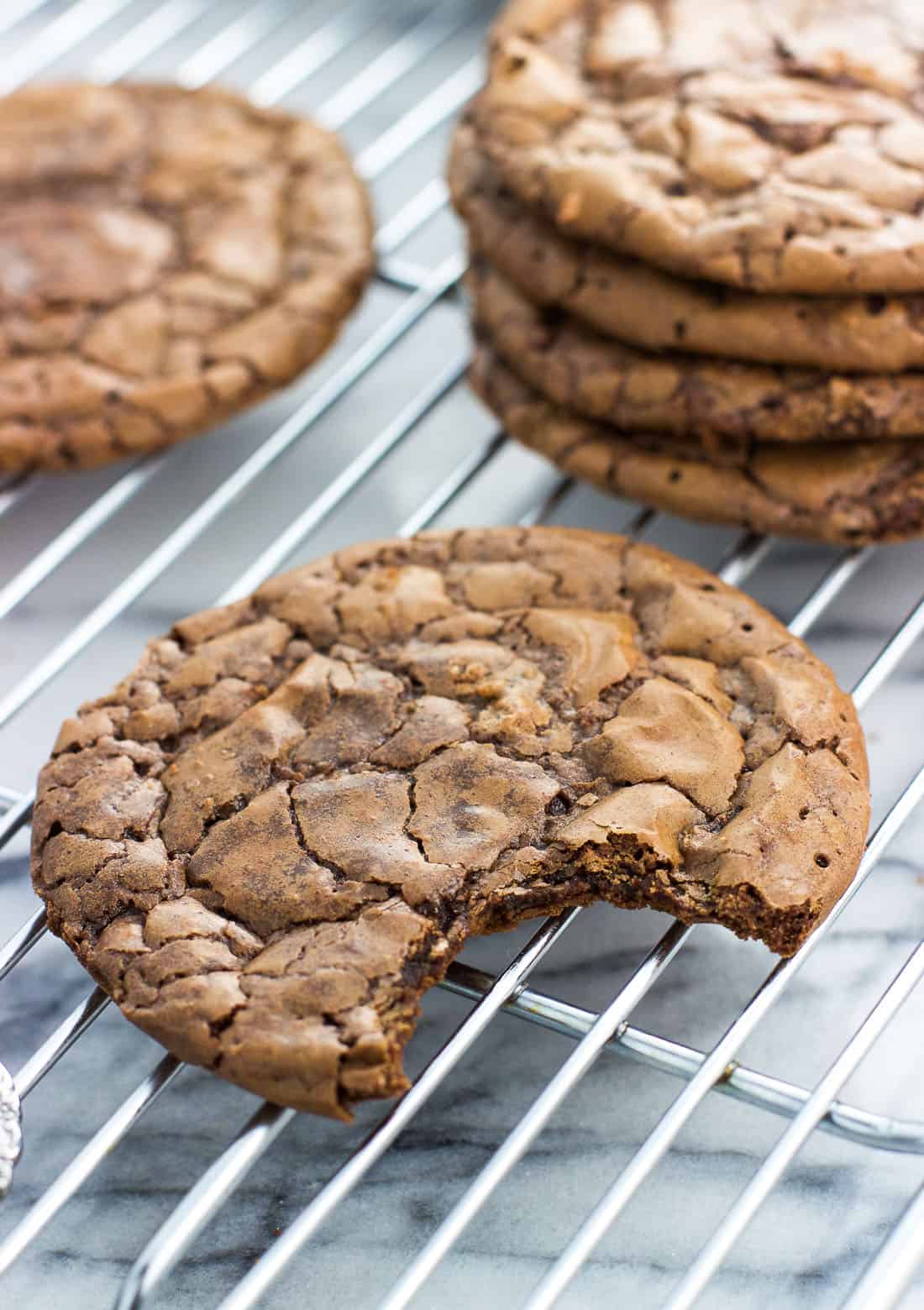 A bite taken out of a brownie cookie on a wire rack