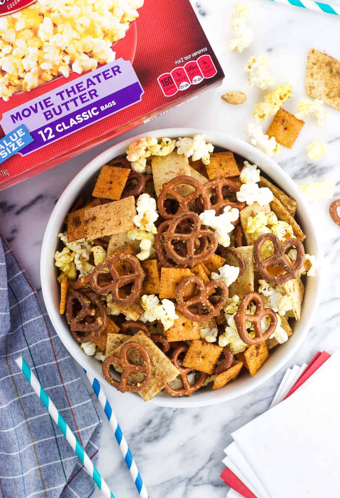 An overhead shot of a bowl of popcorn snack mix next to a box of popcorn