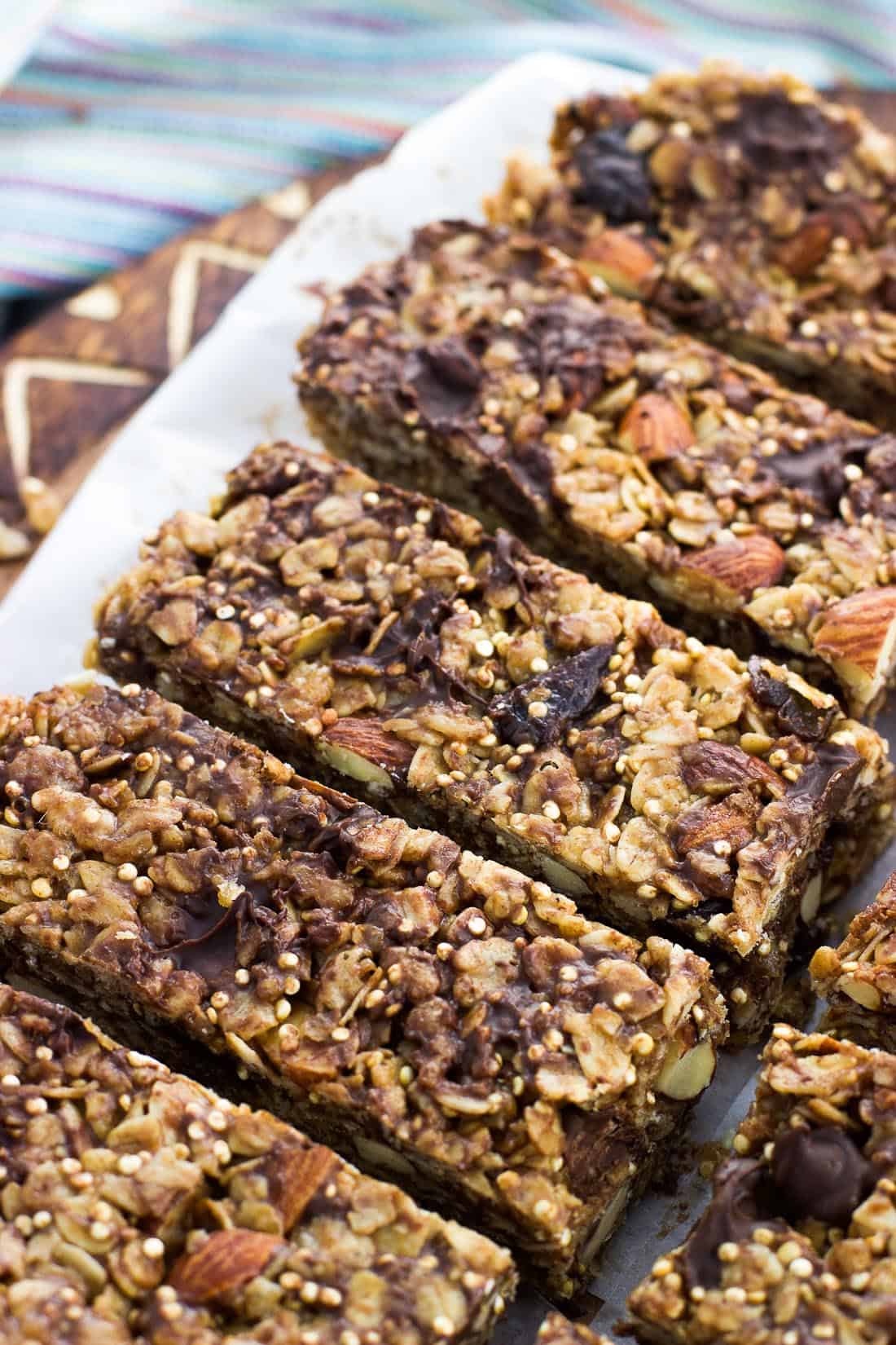 The granola bar slab sliced into bars on a piece of parchment on a wooden board