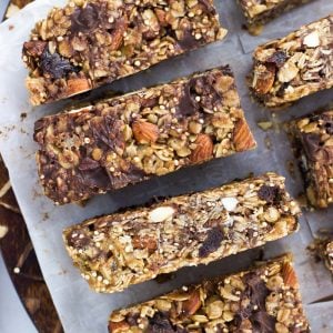 Sliced granola bars on a piece of parchment on top of a round wooden cutting board