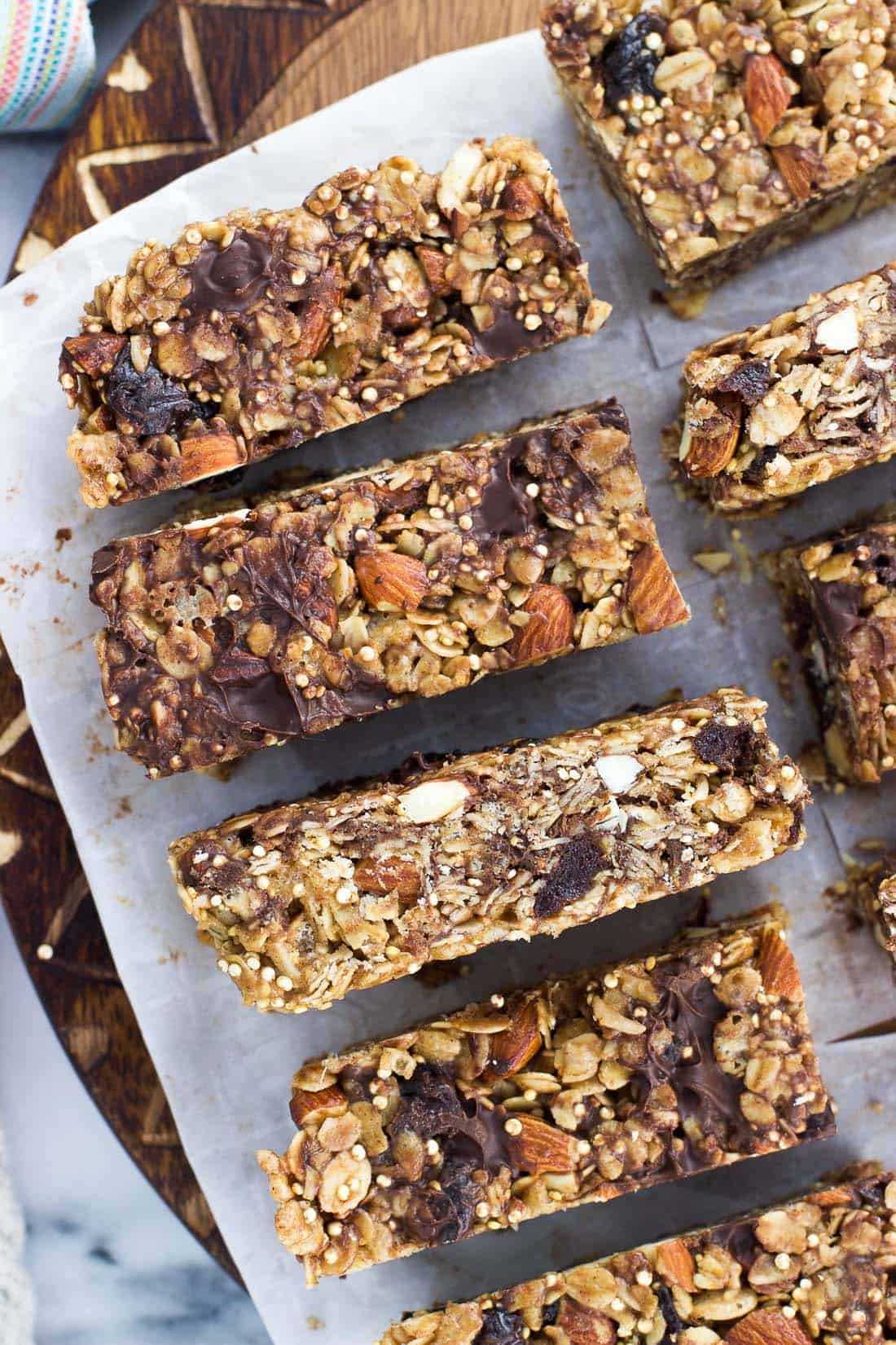 Sliced granola bars on a piece of parchment on top of a round wooden cutting board