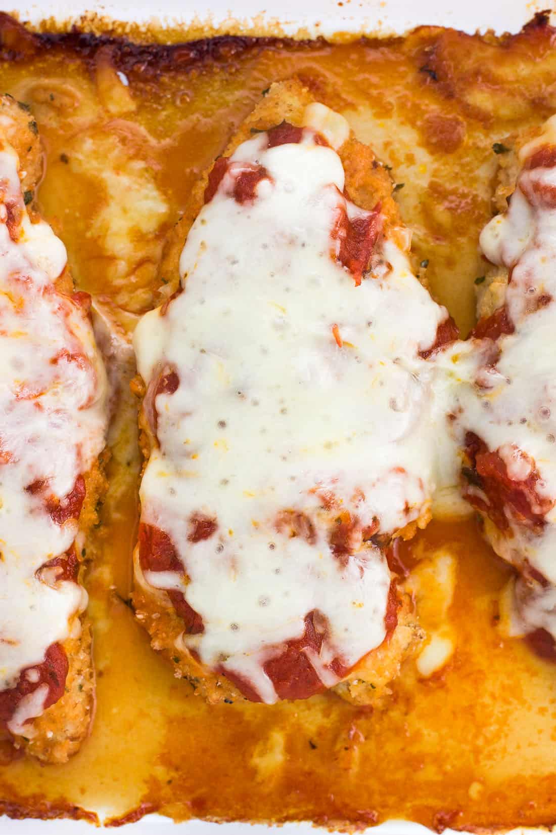 An overhead picture of baked chicken Parmesan cutlets in the baking dish.
