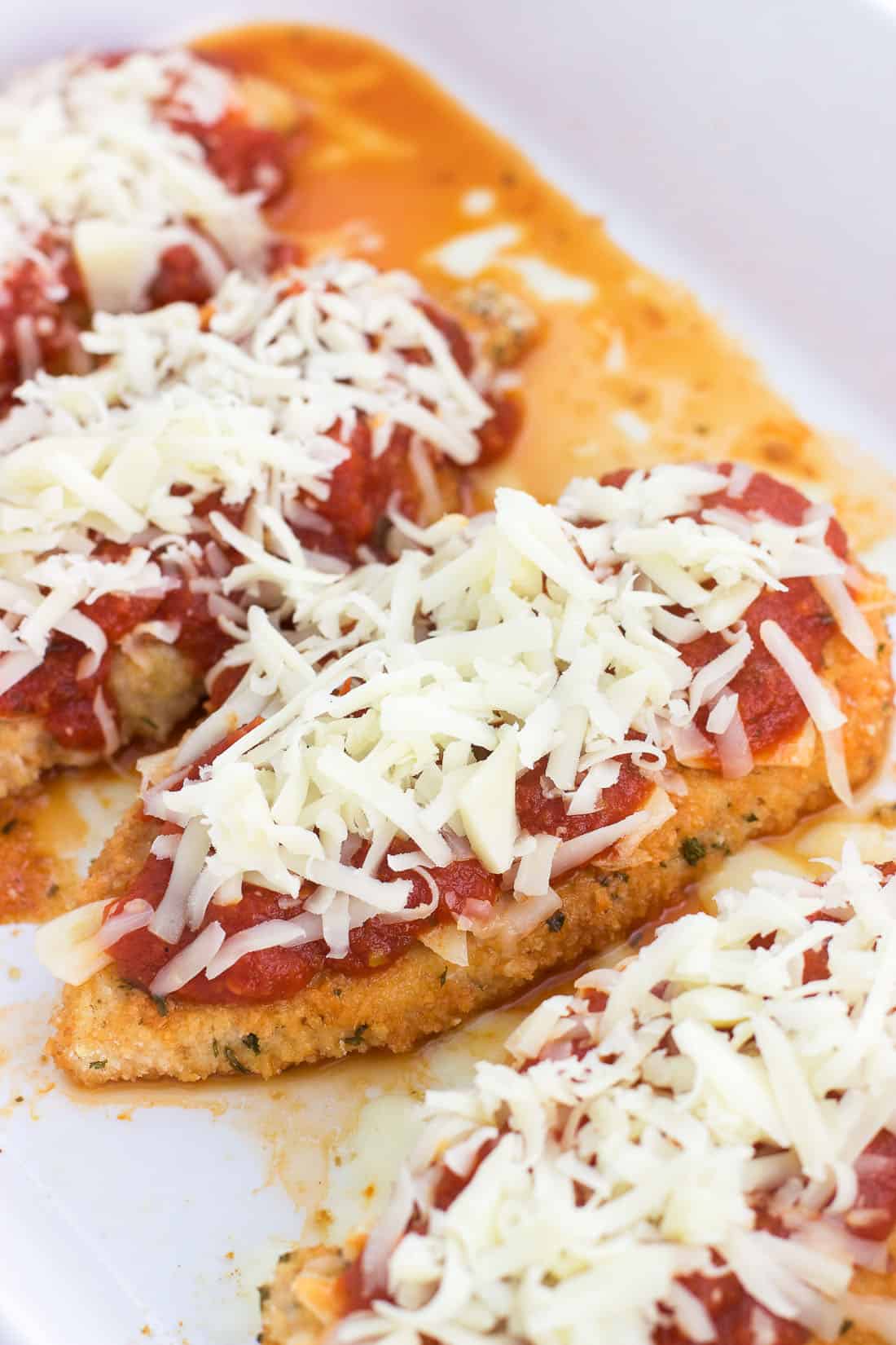 Chicken cutlets coated in breadcrumbs, marinara sauce, Parmesan cheese, and shredded mozzarella about to bake.