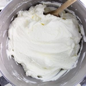 A stand mixer bowl of stabilized whipped cream with a wooden spoon.