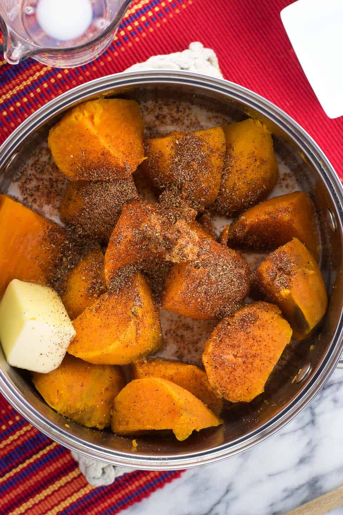 Sweet potato segments, butter, milk, and spices in a saucepan before mashing