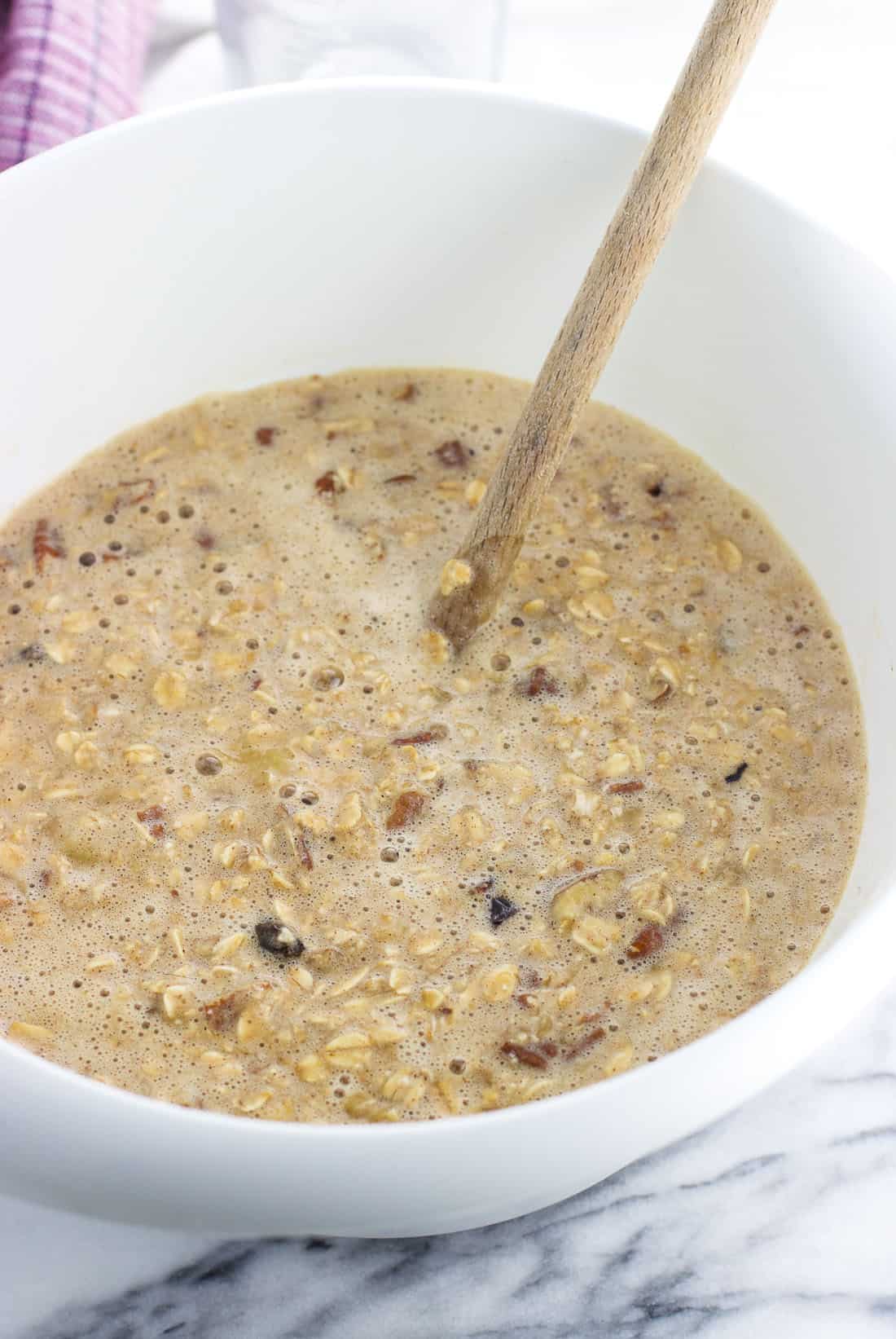 Oatmeal batter in a mixing bowl with a wooden spoon.