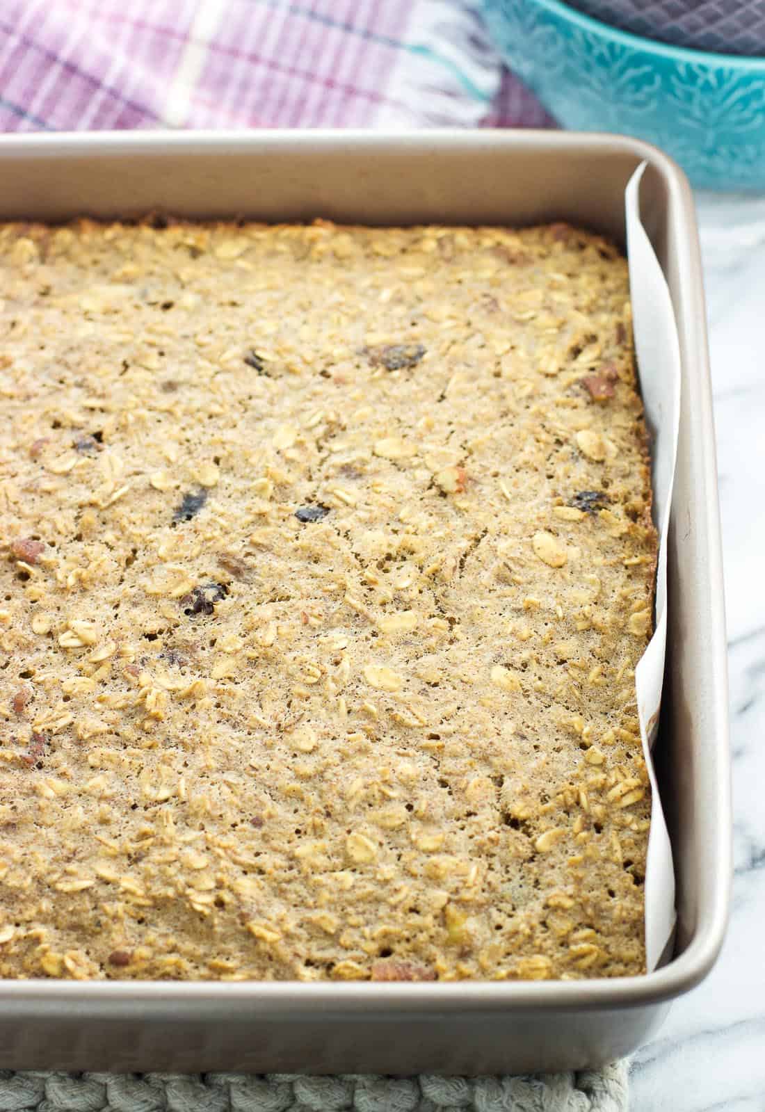Baked oatmeal in a parchment-lined square pan.