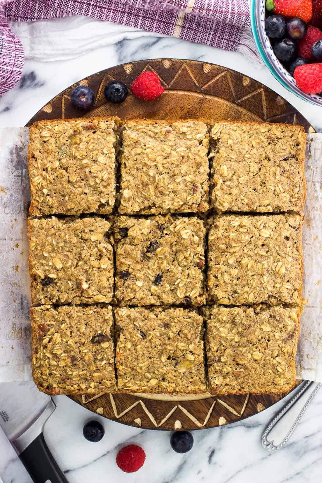 Baked oatmeal sliced into nine pieces on a round wooden serving board.