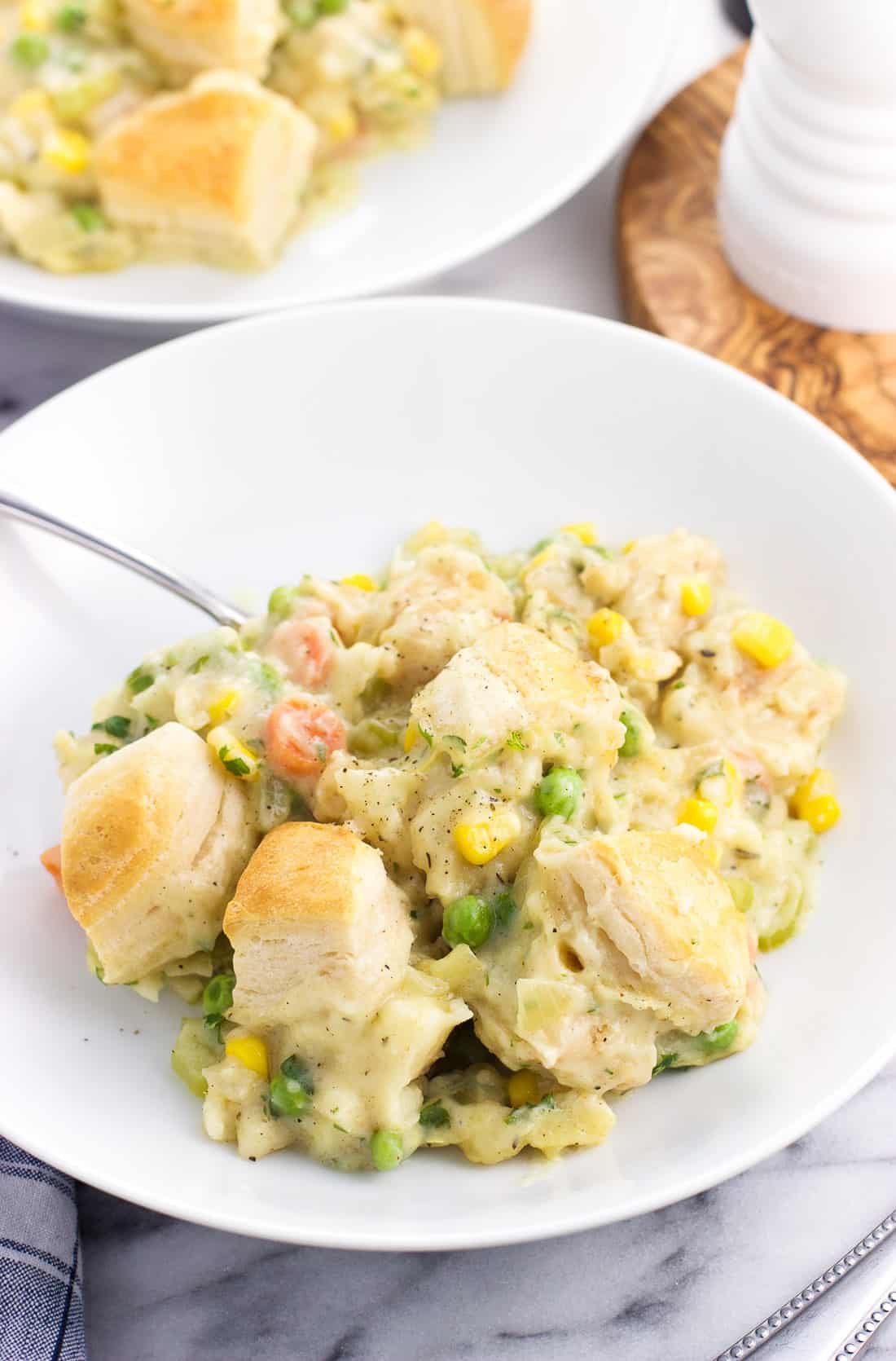 A serving of fish pot pie in a shallow dish with a spoon