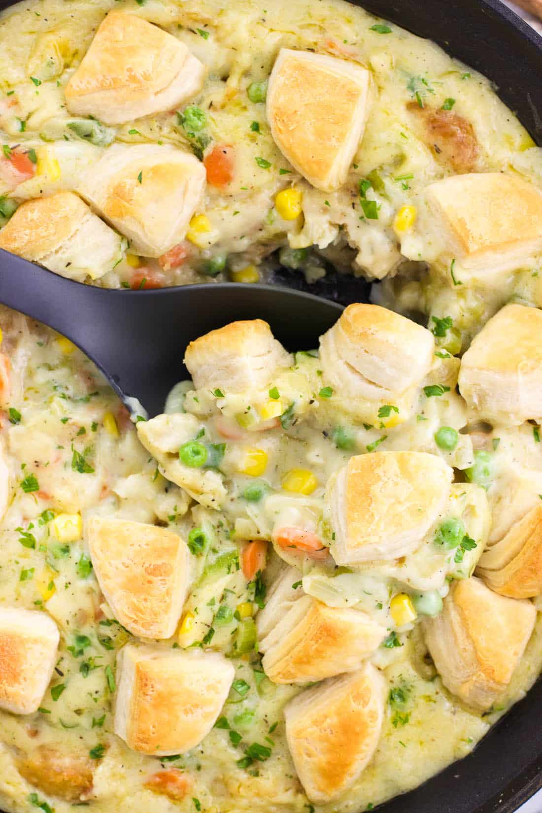 A serving spoon scooped into the skillet pot pie