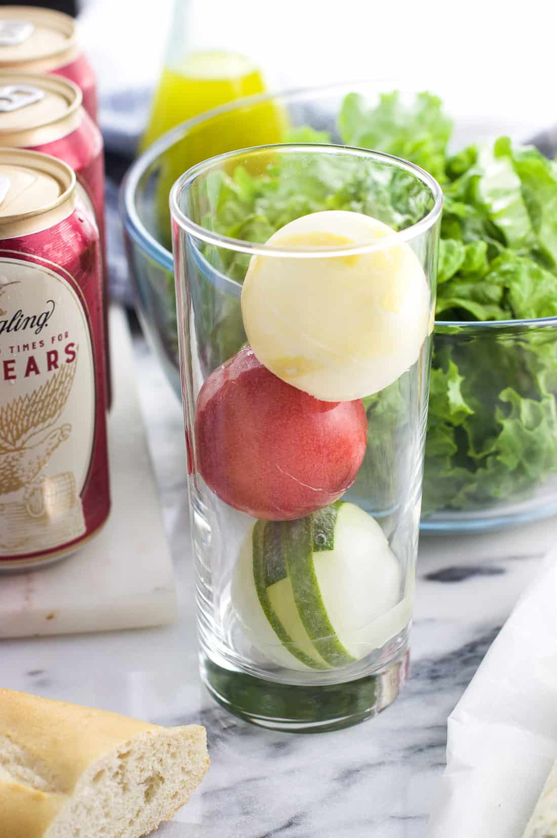 Fruit slices frozen into large ice spheres in a glass .