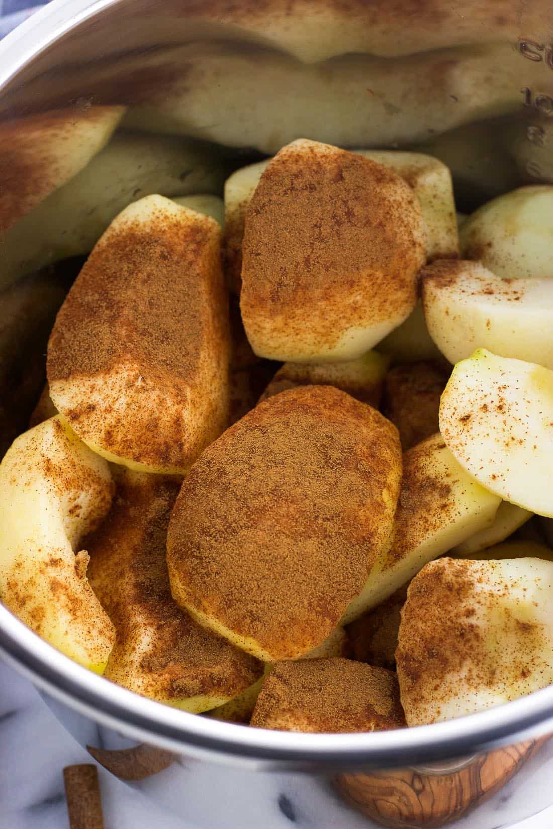 Peeled and quartered apples pre-cook in the Instant Pot, covered in ground cinnamon.