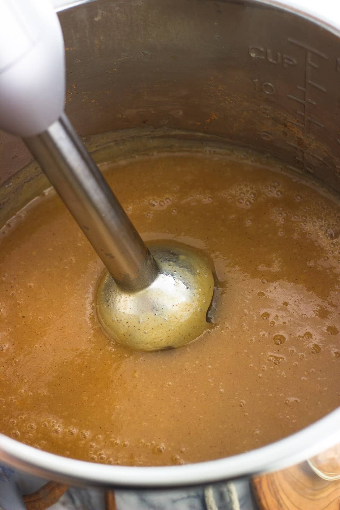An immersion blender pureeing the cooked applesauce in the Instant Pot.