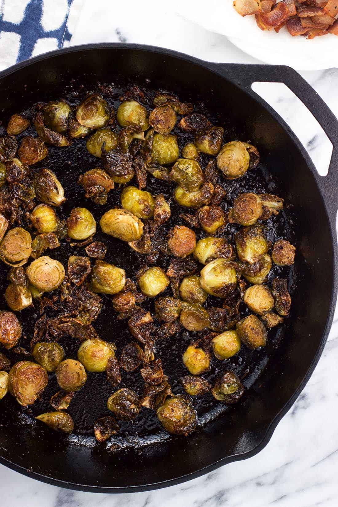 An overhead view of roasted brussels sprouts in a cast iron skillet