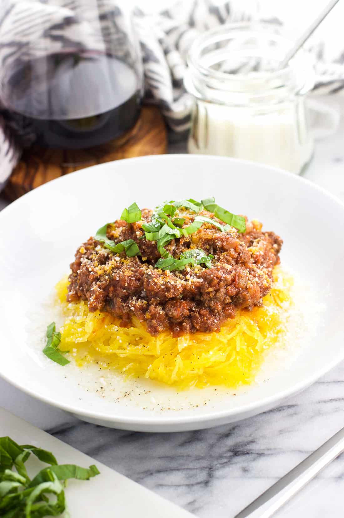Spaghetti squash bolognese in a bowl with Pecorino Romano and basil on top.