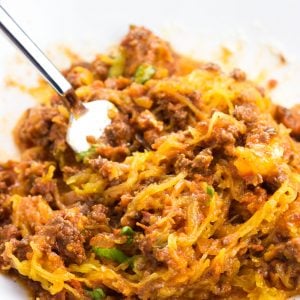 A serving of bolognese sauce and spaghetti squash all stirred up in a bowl with a fork